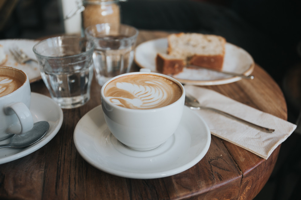 Coffee cups on wooden table with cake and glasses of water