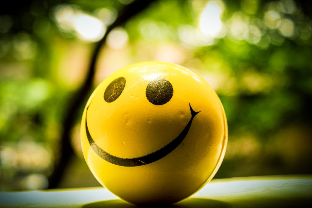 Yellow ball with smiley face sitting on a counter in front of a faded natural background